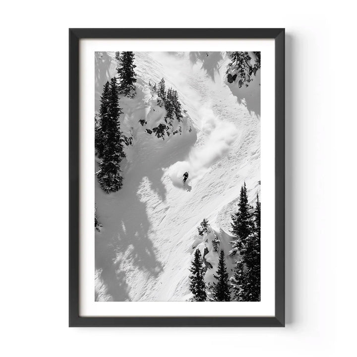 Framed black and white photograph of a skier descending a snowy mountain with trees.