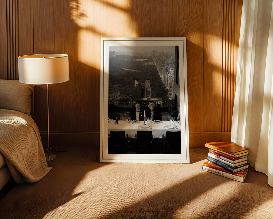 Framed artwork on a wooden floor with a lamp and books in the background