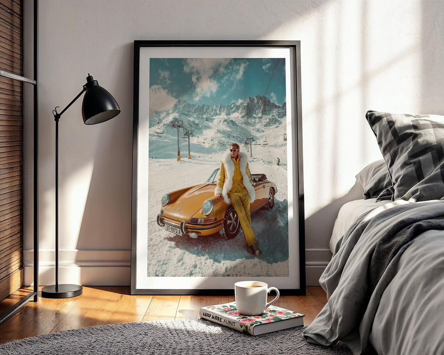 Framed artwork of a woman in yellow by a yellow car in a snowy landscape, placed on a wooden floor in a room with a bed and lamp.