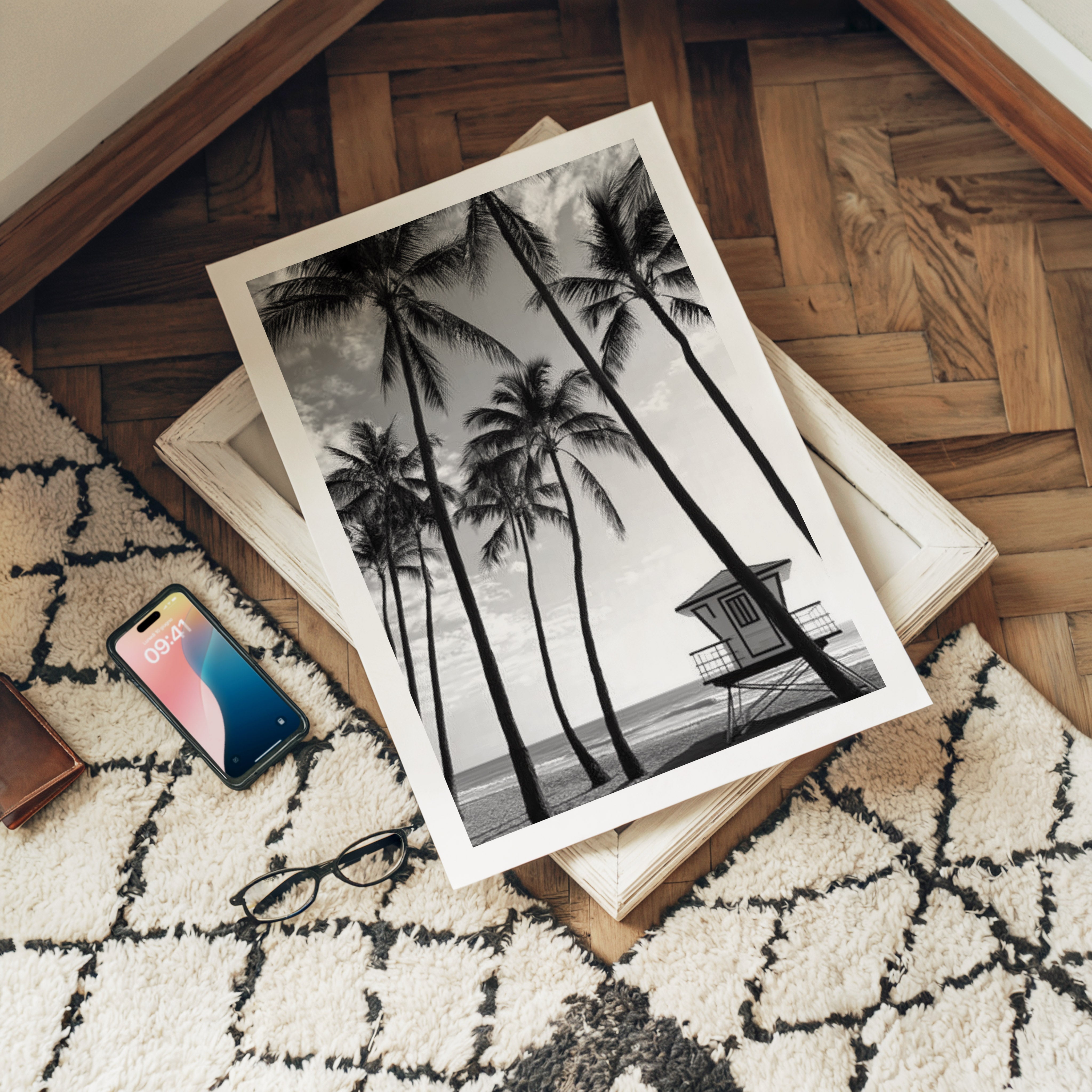 Black and white palm tree print on a wooden floor with a phone and glasses nearby.