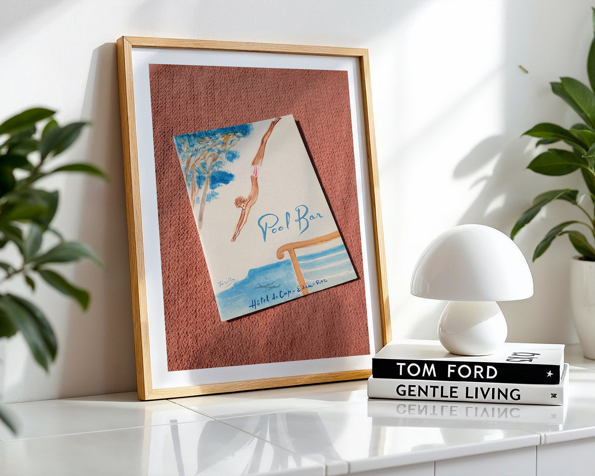 Framed poster on a shelf with a lamp and books in the background