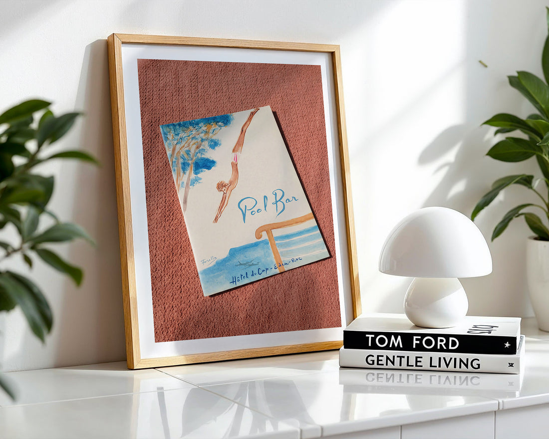 Framed poster on a shelf with a lamp and books in the background