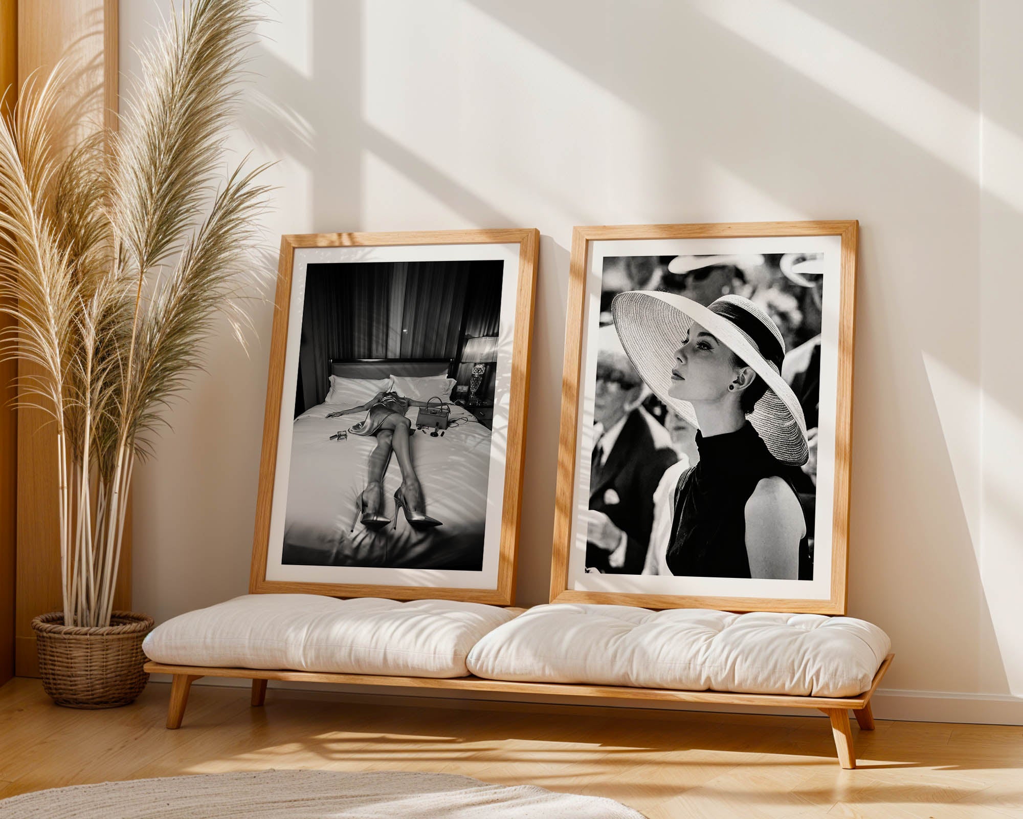 Two framed black and white photos on a wooden bench with a plant in the background.