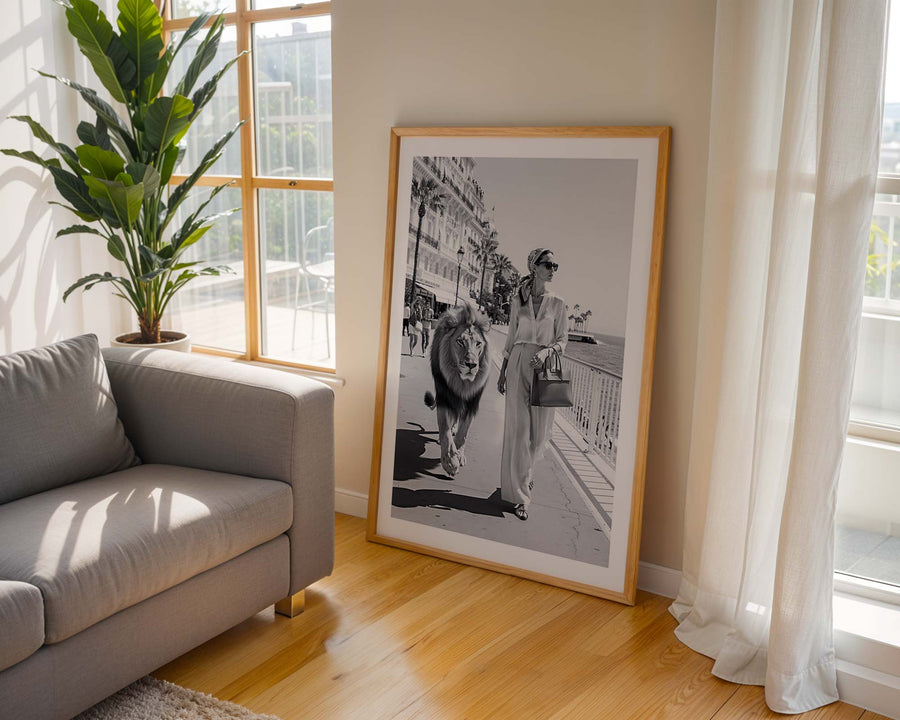 Framed black and white artwork of a woman with a dog on a city street, placed in a living room.