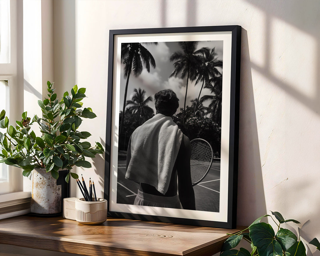 Framed black and white photo of a person with a tennis racket on a wooden shelf with plants.