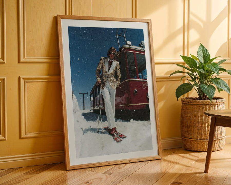 Framed artwork of a person skiing next to a vintage vehicle on a wooden floor with a plant in the background.