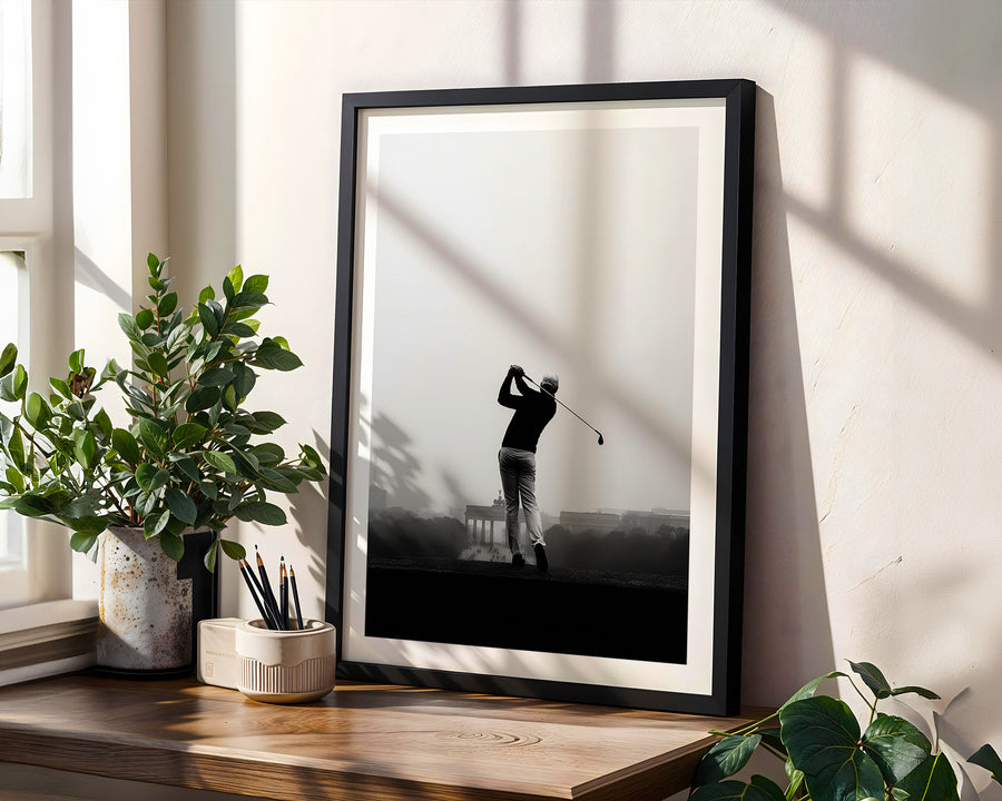 Framed black and white print of a golfer on a wooden shelf with plants