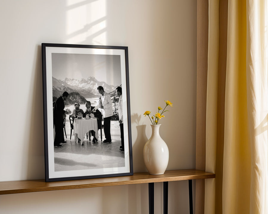 Framed black and white photograph on a wooden shelf with a vase of flowers.