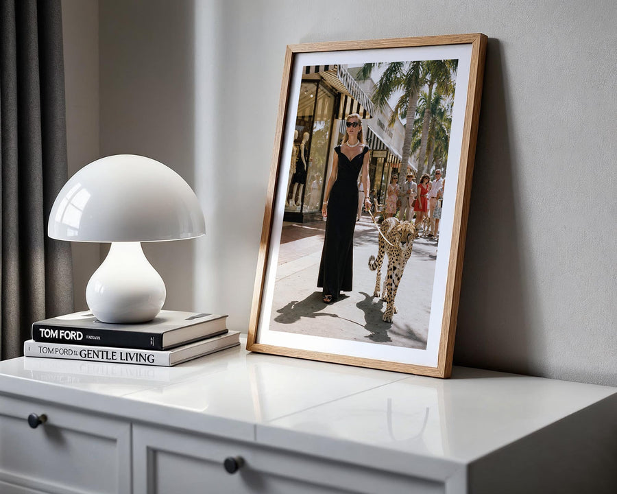 Framed photograph of a woman in a black dress on a white surface with a lamp and books.