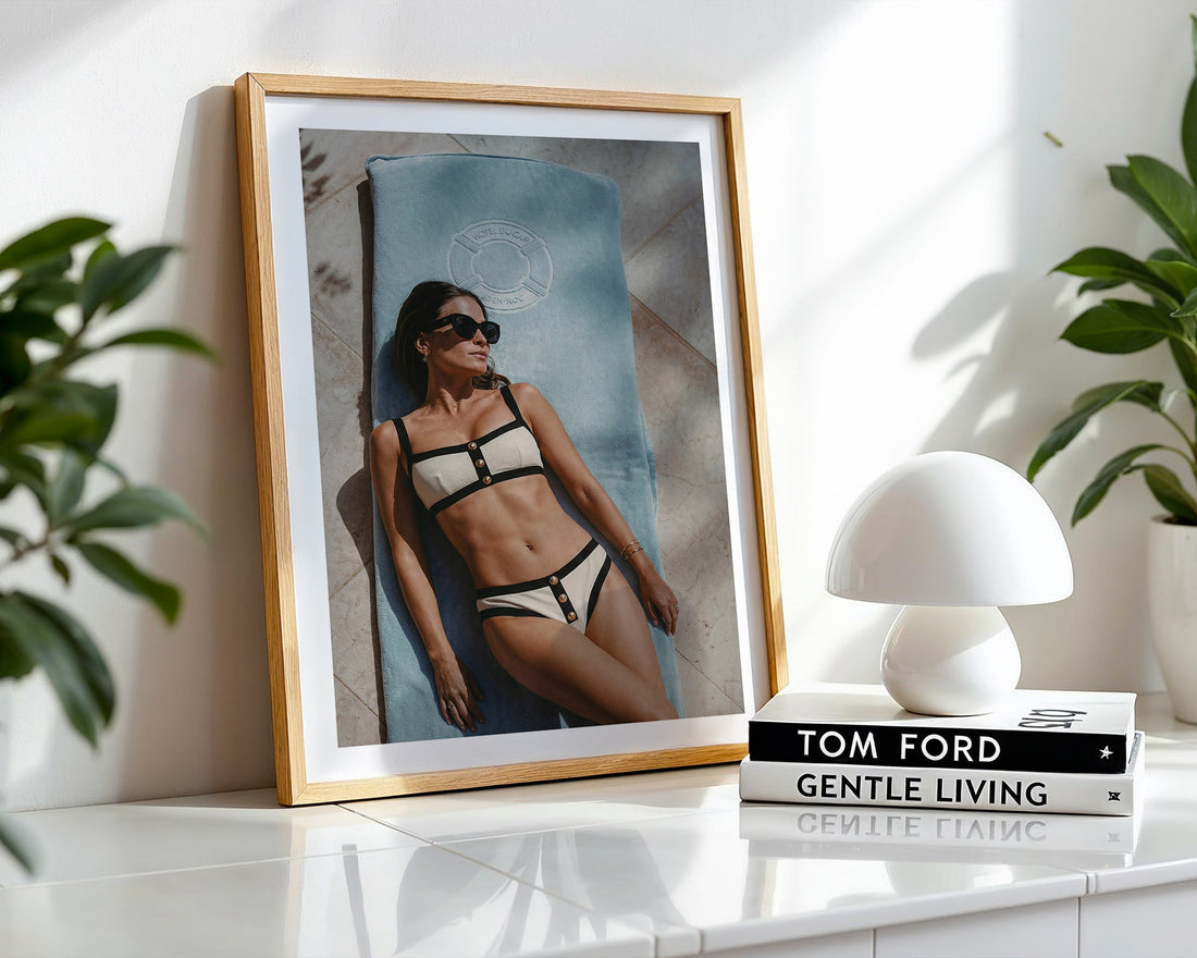 Framed photo of a woman in a Chanel bikini on a shelf with a white lamp and 'Tom Ford Gentle Living' book.