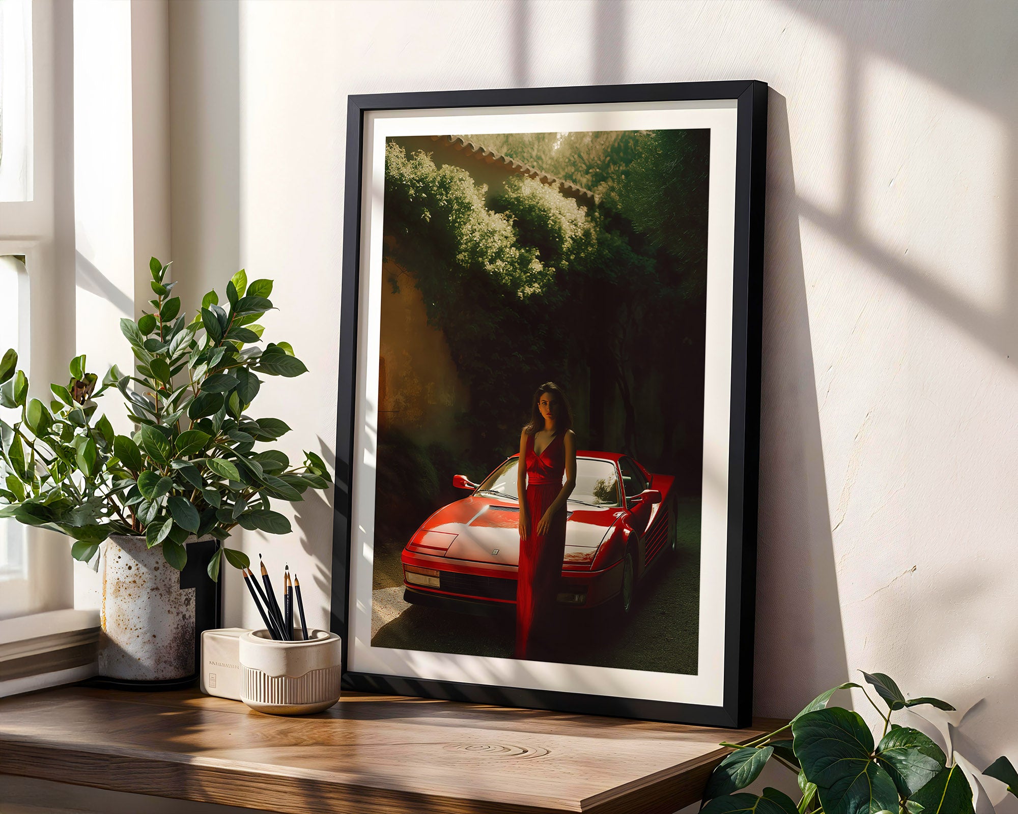 Framed artwork of a woman in a red dress standing next to a red car on a wooden shelf with plants.