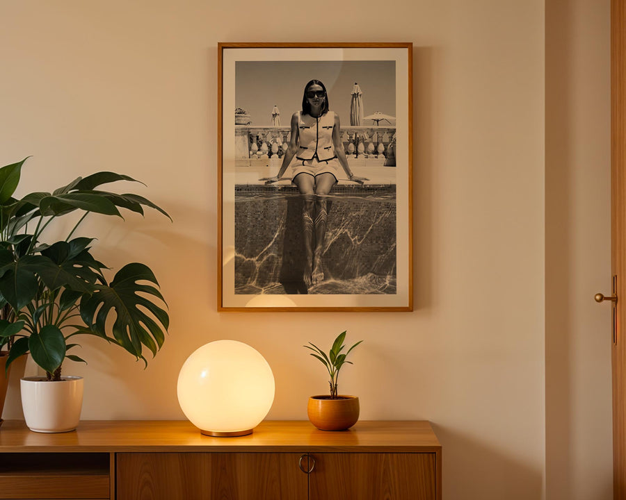 Framed black and white photograph of a woman on a wall above a wooden cabinet with decorative items.