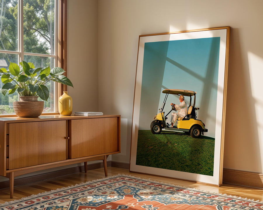 Framed photograph of a person on a golf cart in a room with a wooden sideboard and decorative rug.