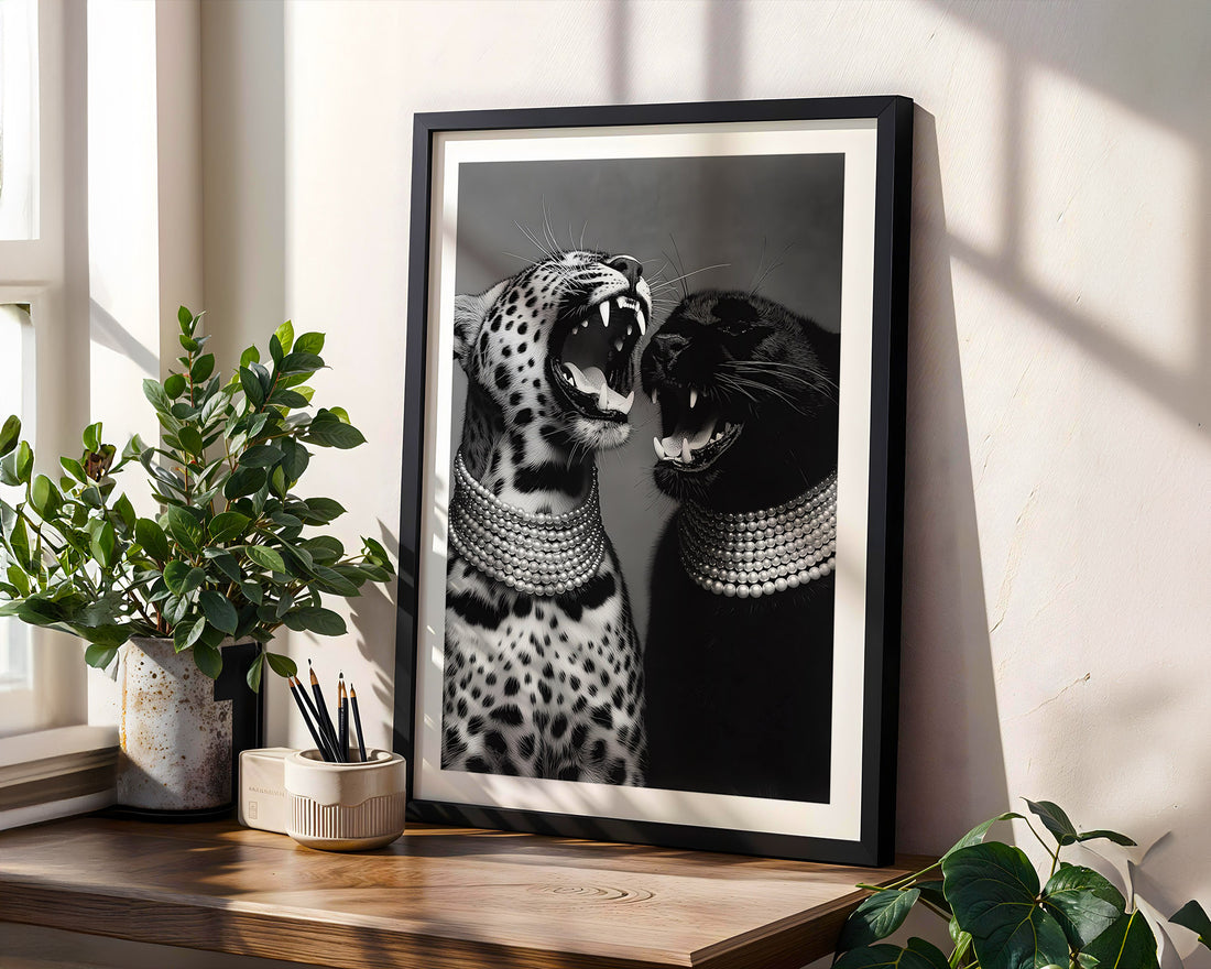 Framed artwork of two cats wearing necklaces on a wooden shelf with plants.