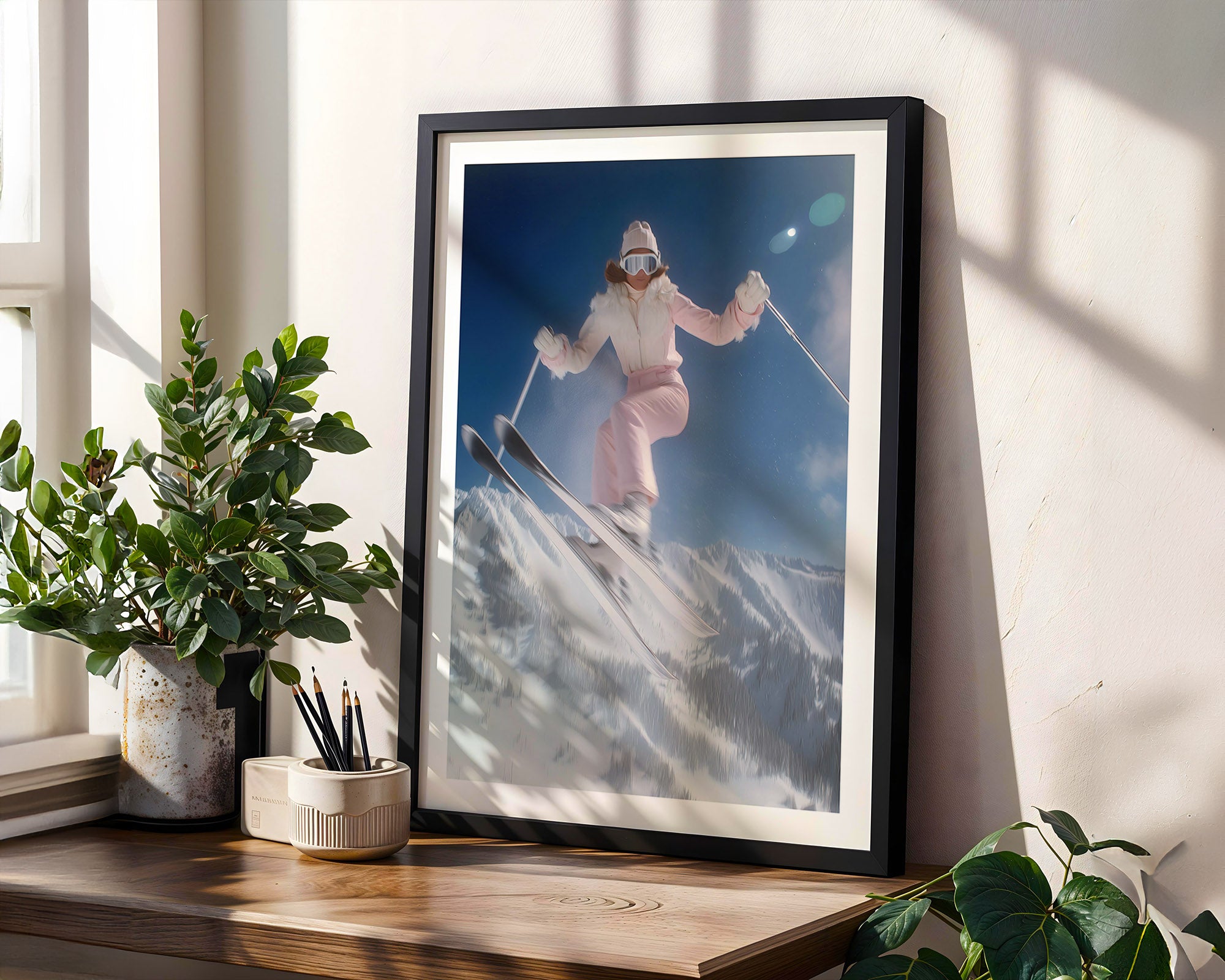 Framed artwork of a skier on a snowy mountain displayed on a wooden shelf with plants.