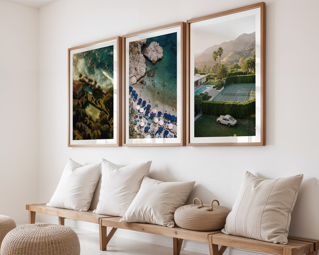 Three framed artworks on a wall above a wooden bench with cushions.