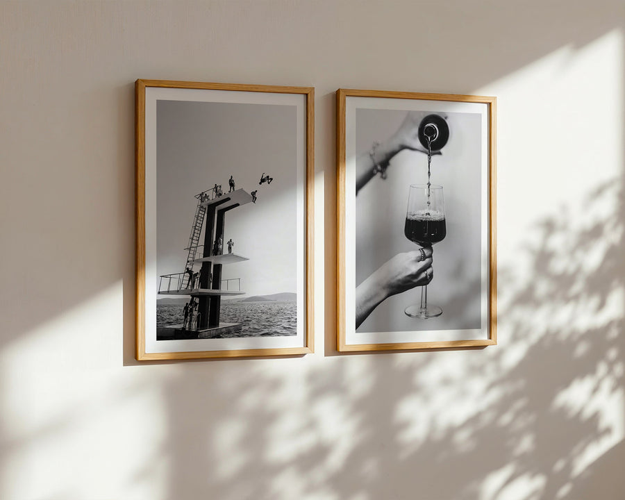 Two framed black and white photographs on a wall with sunlight casting shadows.