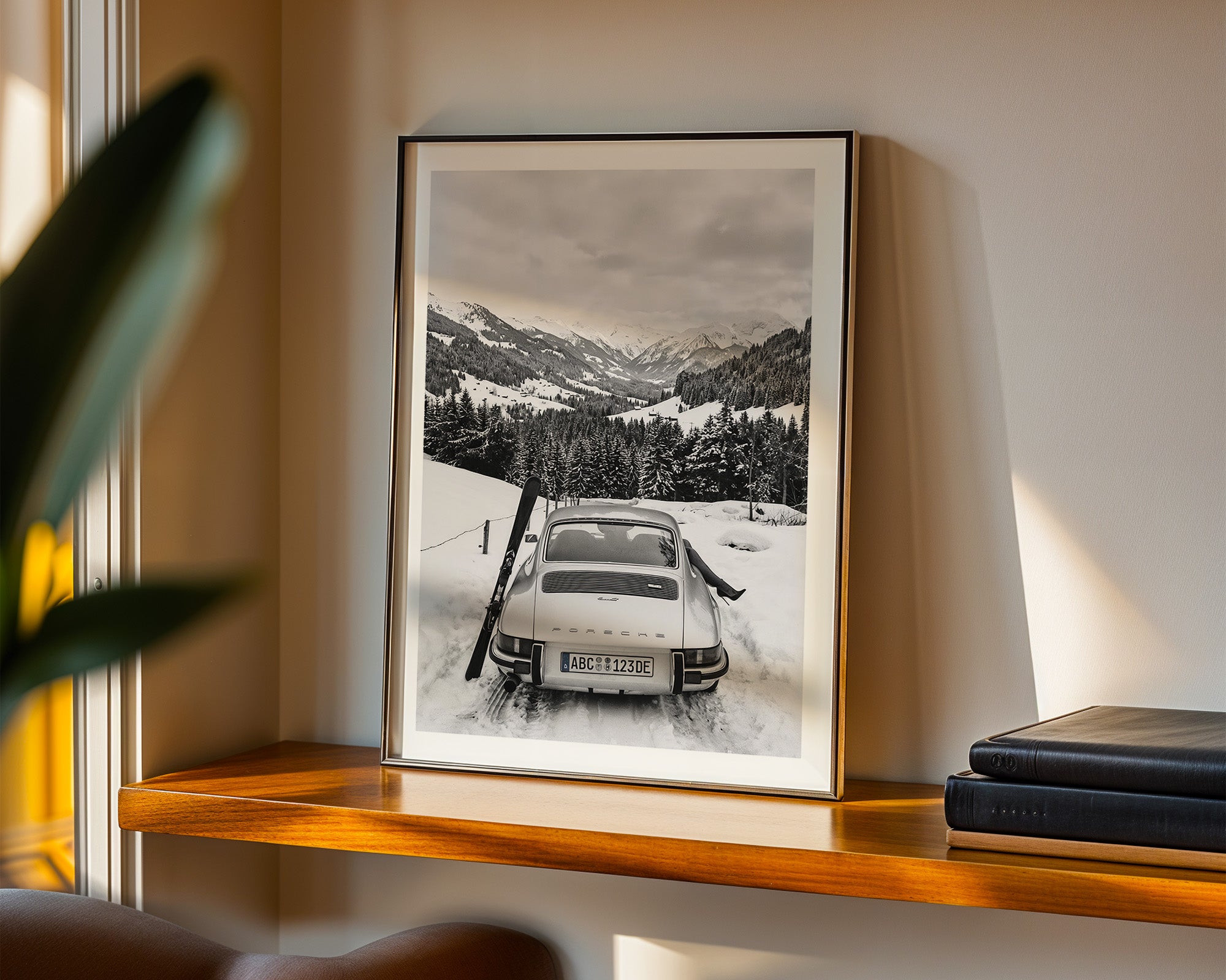 Framed black and white photograph of a snowy landscape with a car on a shelf.