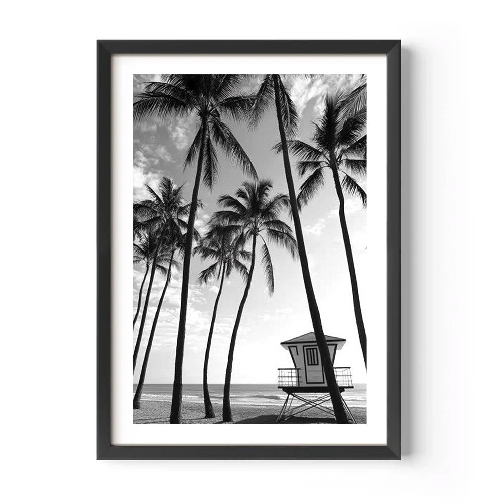 Framed black and white print of a beach scene with palm trees and a lifeguard tower.