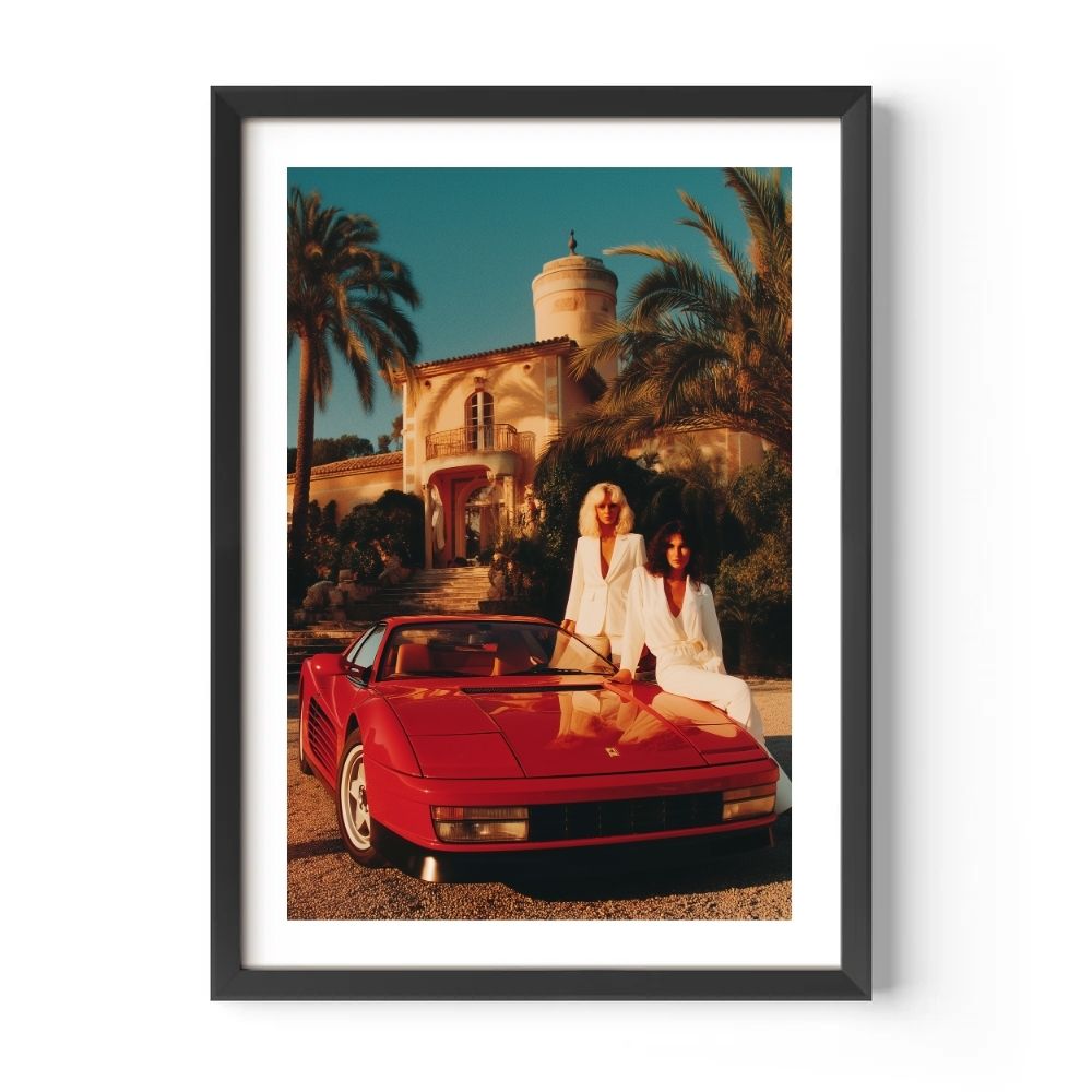 Framed poster of two women in white by a red sports car with palm trees and a building in the background.