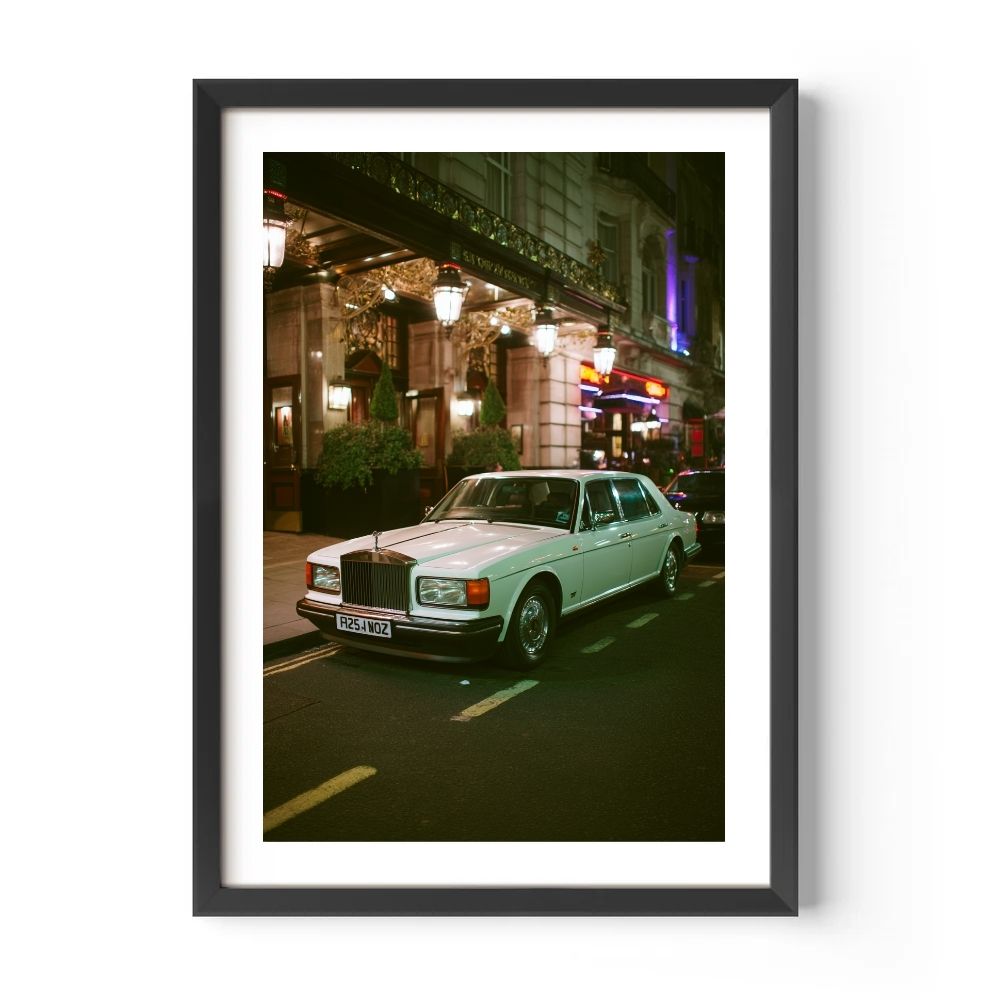 Framed photograph of a white car on a city street at night.