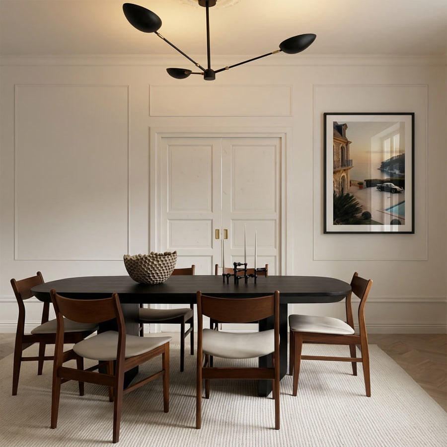 Dining room with a black table and wooden chairs in a modern interior setting.
