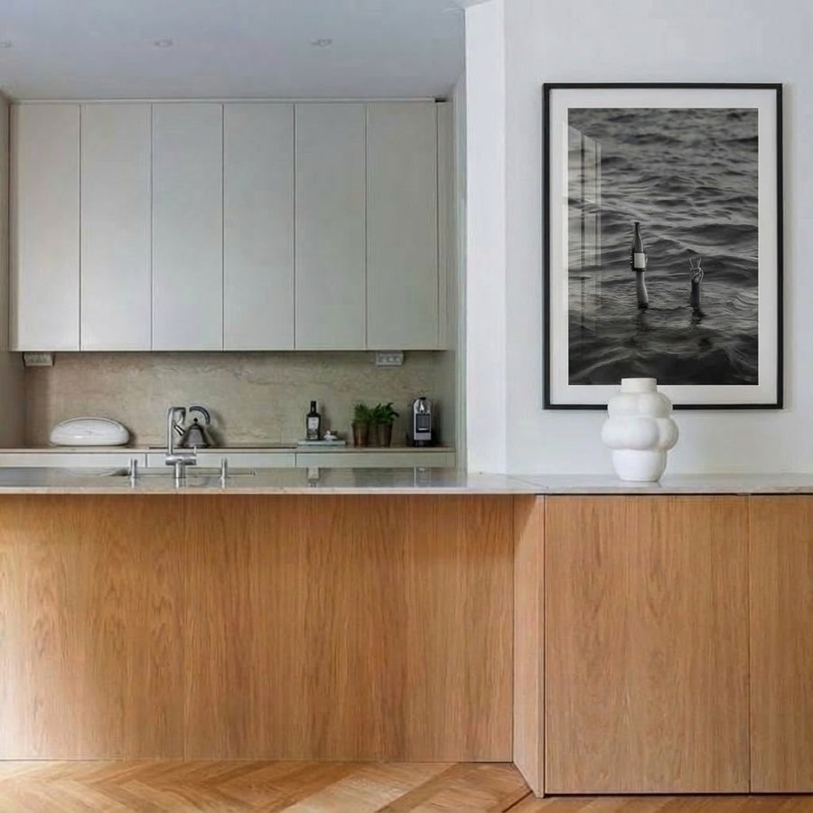 Modern kitchen with wooden cabinets, white countertops, and a framed artwork on the wall.