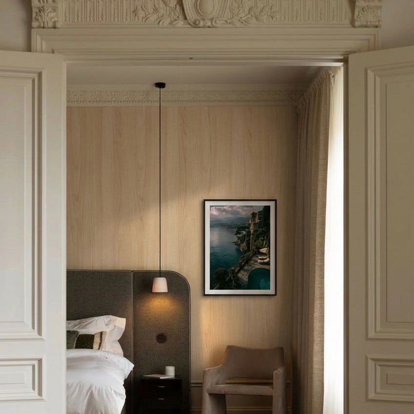Modern bedroom with a bed, lamp, and framed picture on the wall.