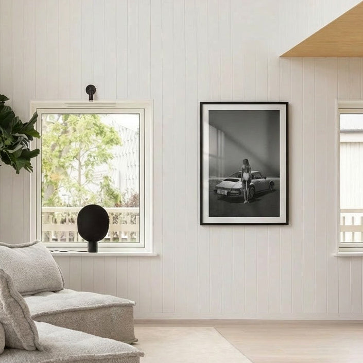 Modern living room with a framed black and white photograph on the wall, a sofa, and a window.