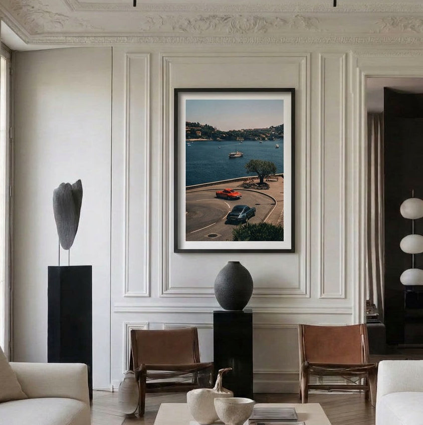 Modern living room with a framed photograph of a coastal road scene on a wall.