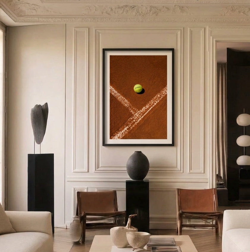 Modern living room with a framed artwork of a tennis ball on a court, chairs, and decor.