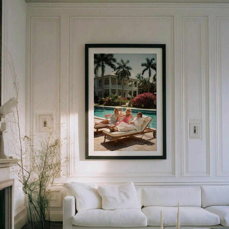 Living room with a white sofa, coffee table, and framed picture of a family by a pool.