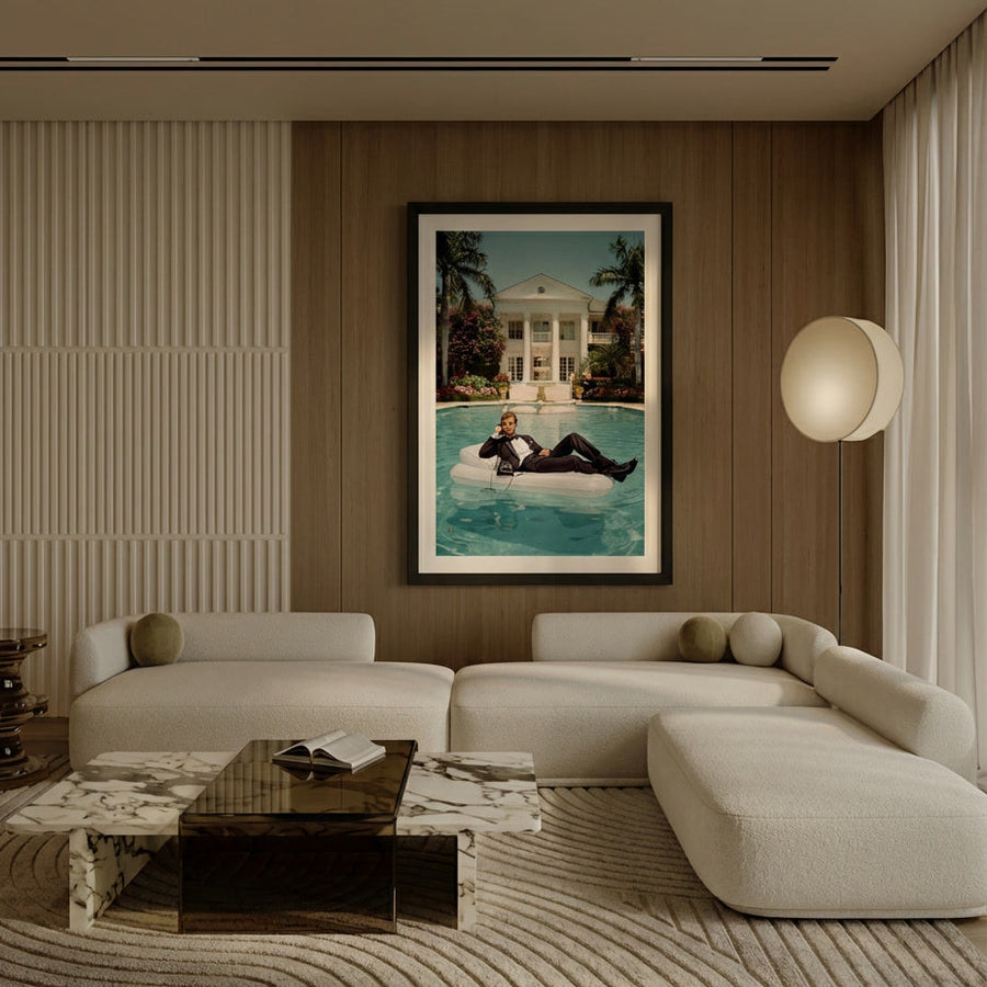 Modern living room with a large sofa, coffee table, and wall art of a person on a pool float.