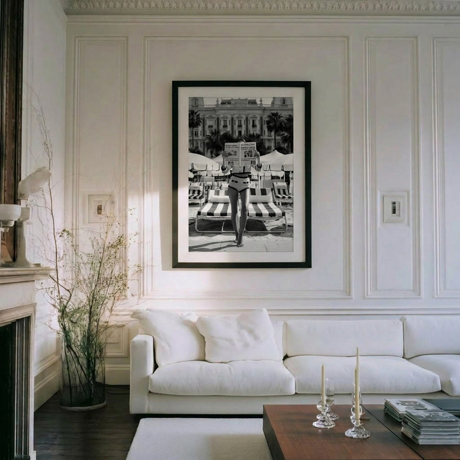 Living room with a white sofa, framed black and white artwork, and decorative items.