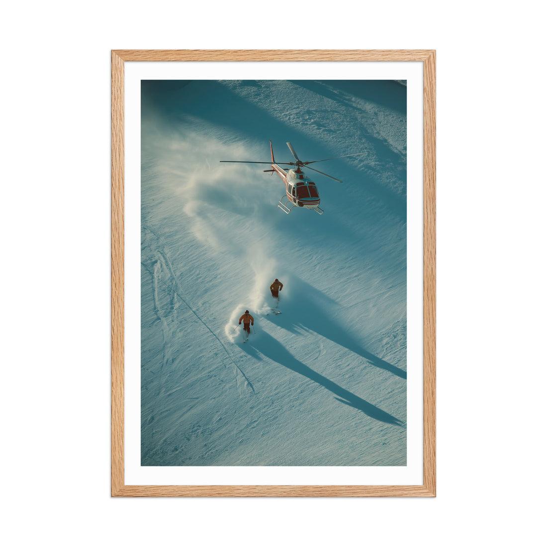 Framed photograph of a helicopter and two people skiing on a snowy landscape.