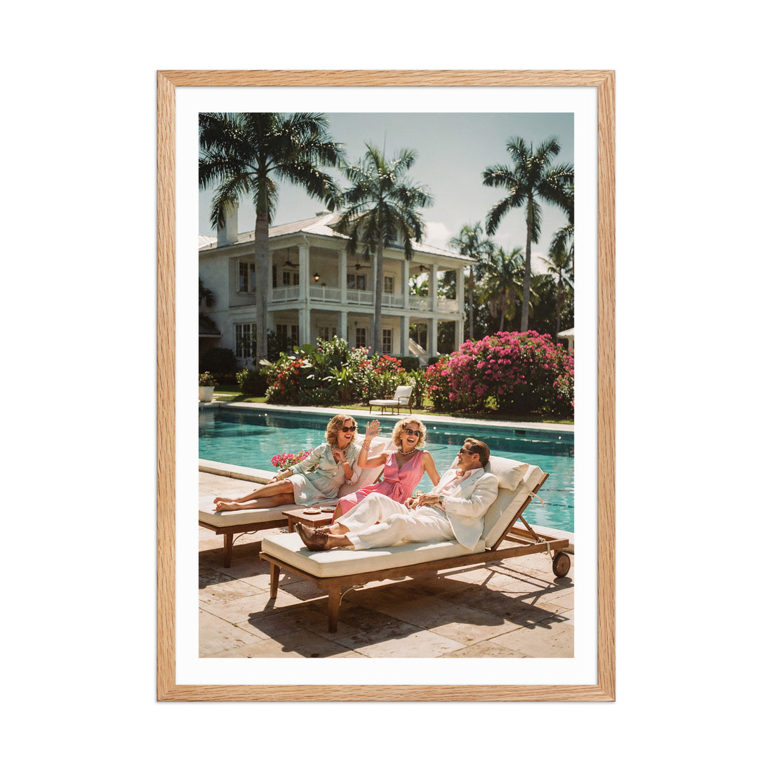 Three people sitting by a pool with palm trees and a large house in the background.