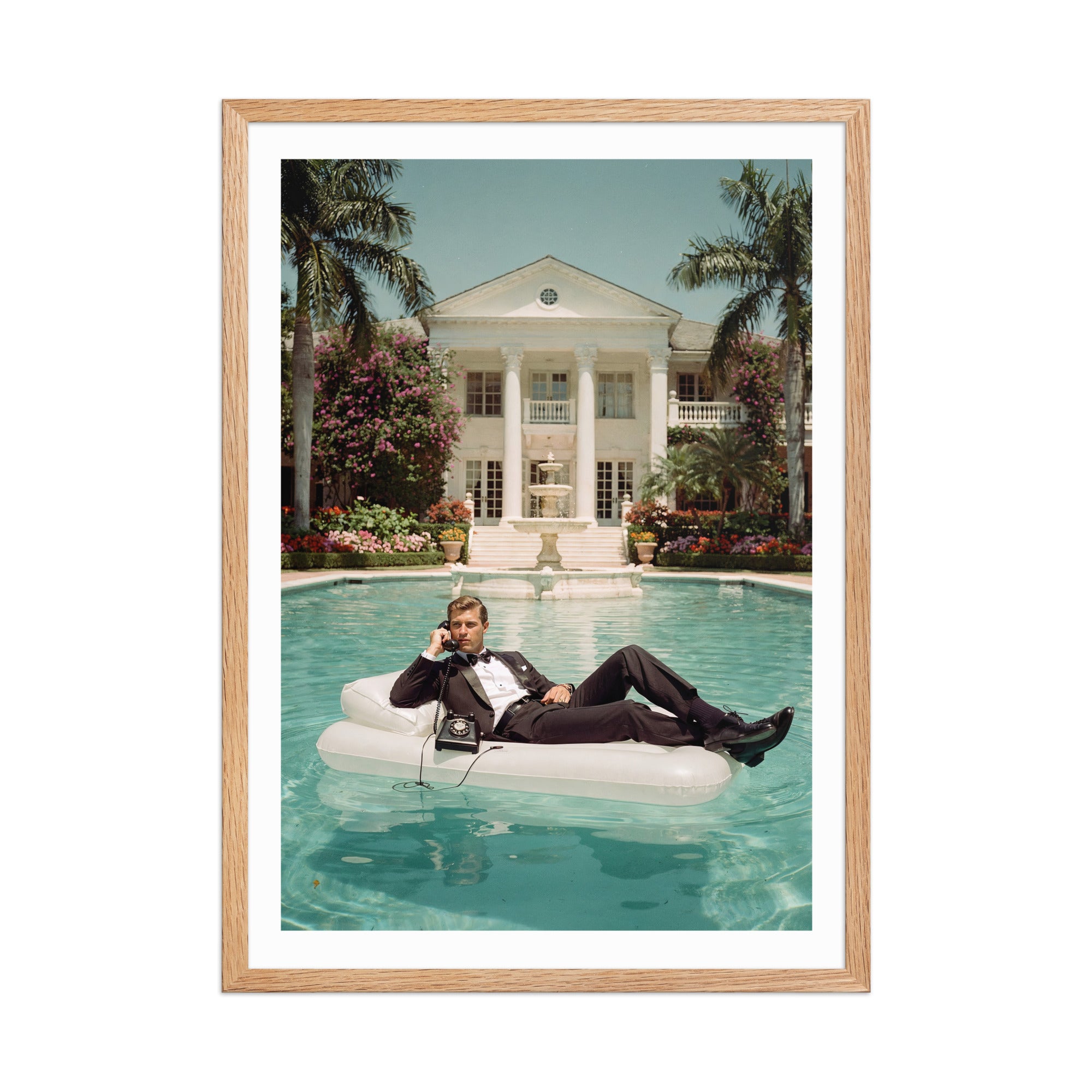 Man lounging on an inflatable raft in a pool with a large house and garden in the background, framed in wood.