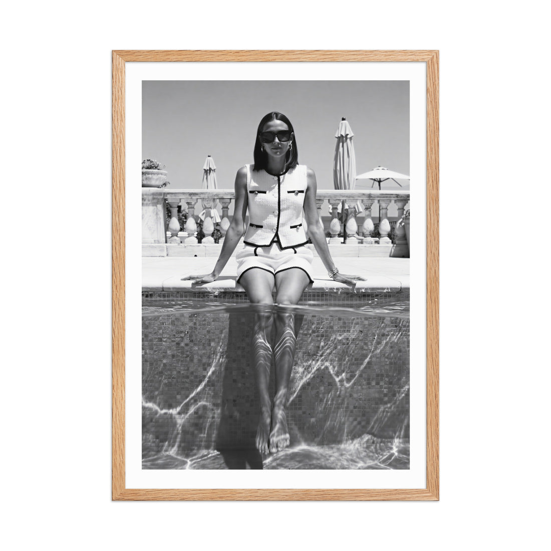 Framed black and white photo of a woman sitting by a pool.