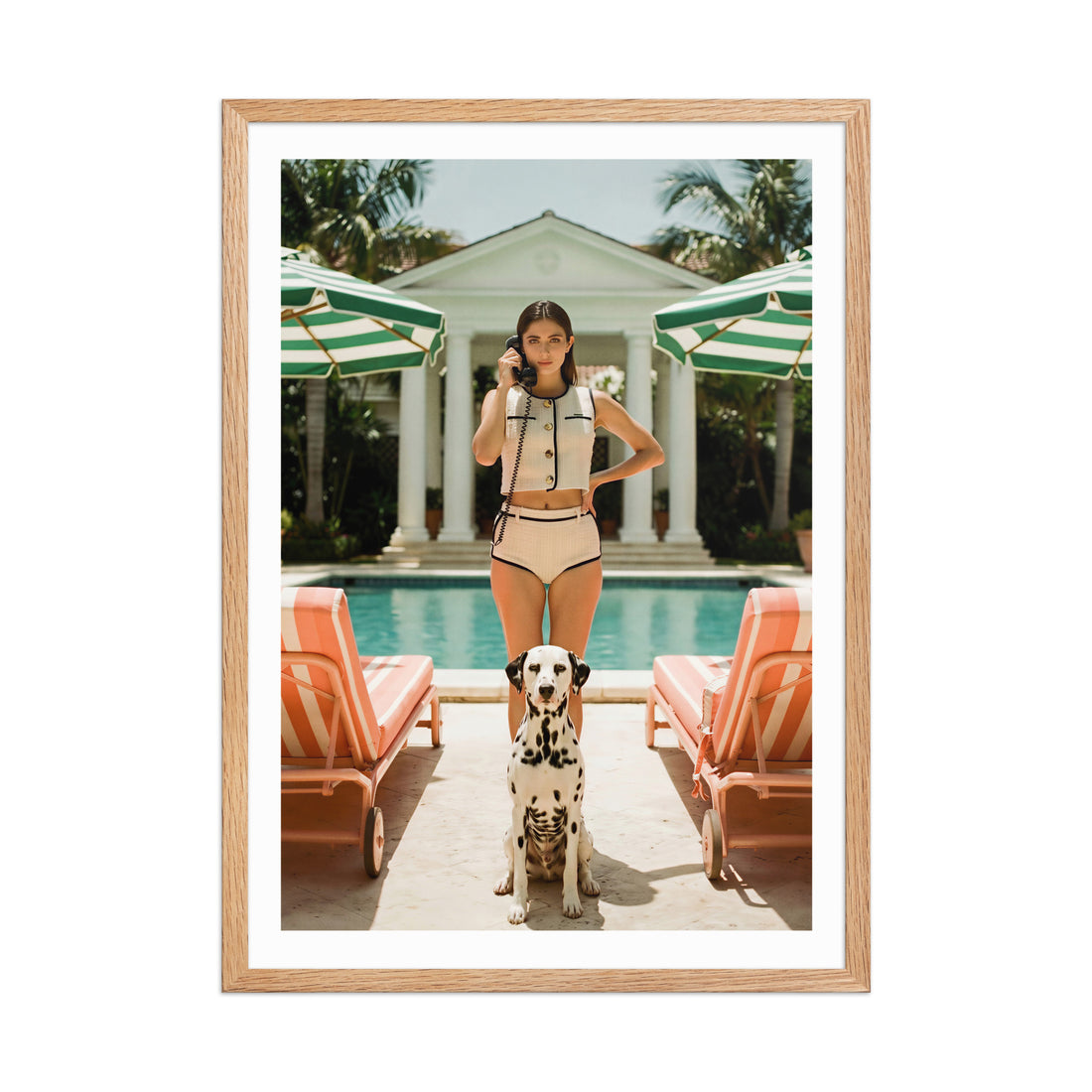 Framed photo of a woman and a Dalmatian dog by a poolside with lounge chairs and umbrellas.