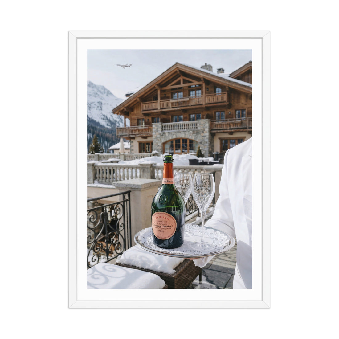 Bottle of champagne and glasses on a tray with a snowy mountain backdrop