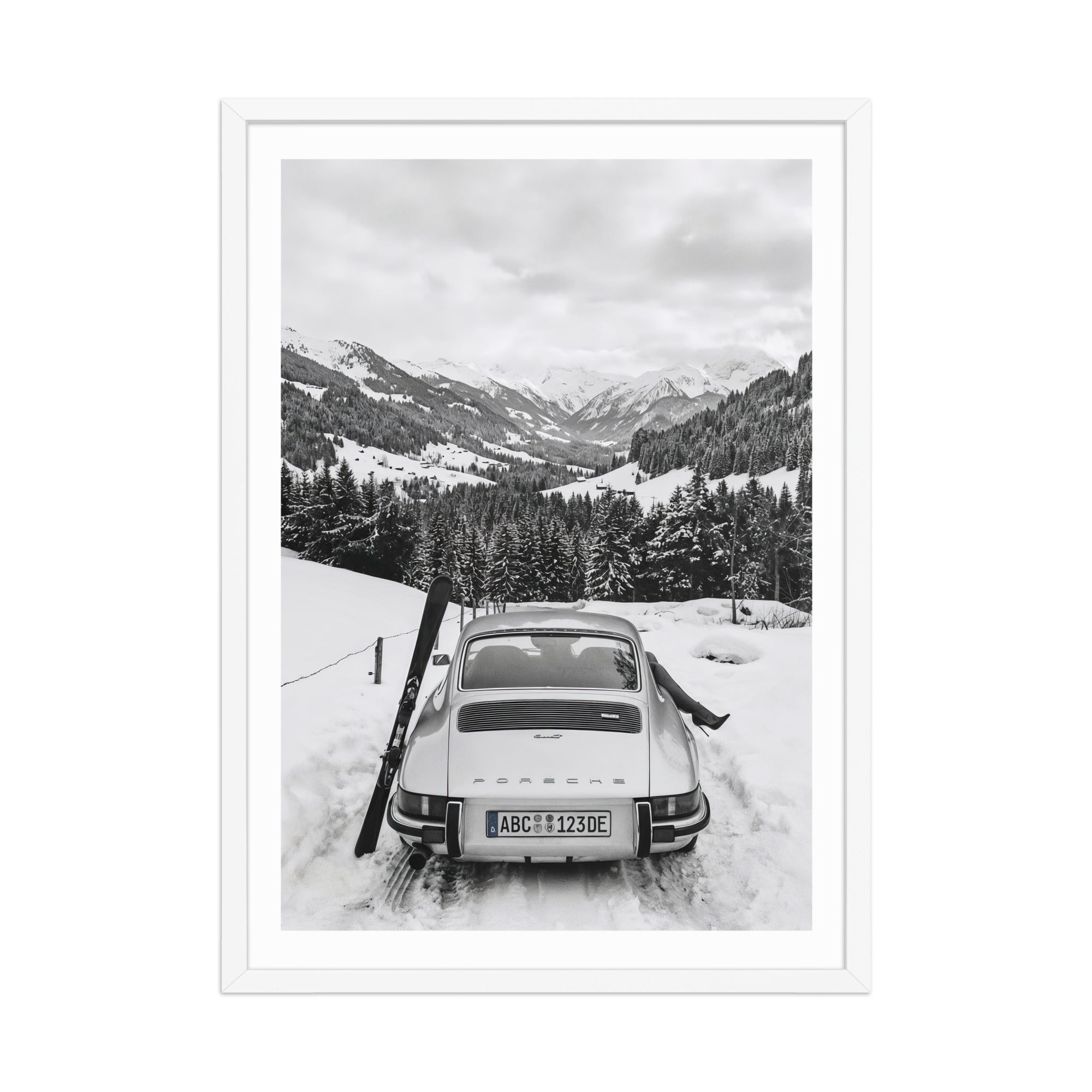 Vintage car in a snowy landscape with mountains and trees.