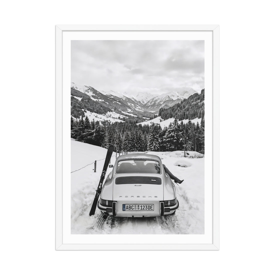 Vintage car in a snowy landscape with mountains and trees.