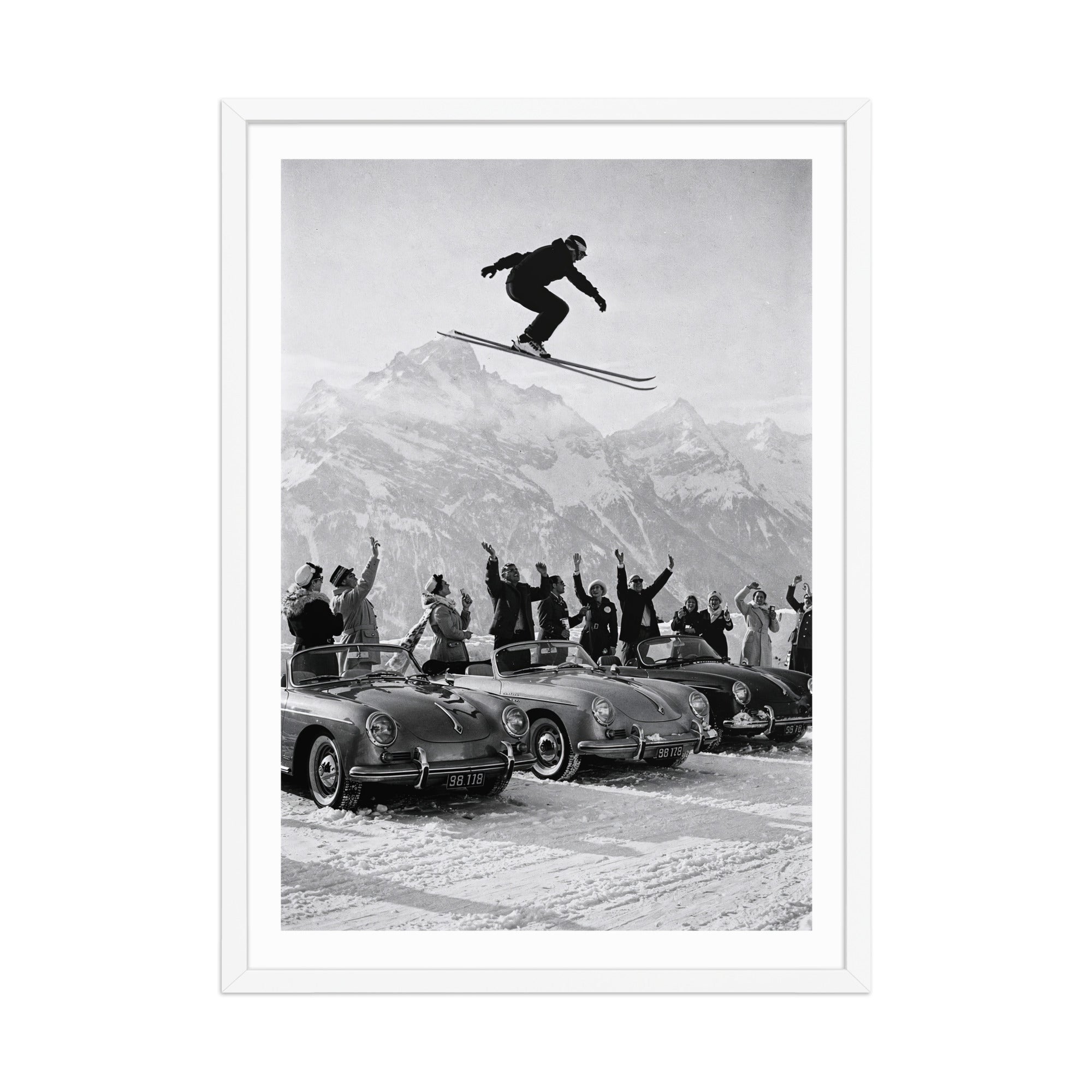 Framed black and white print of a skier jumping over cars with a mountainous background.
