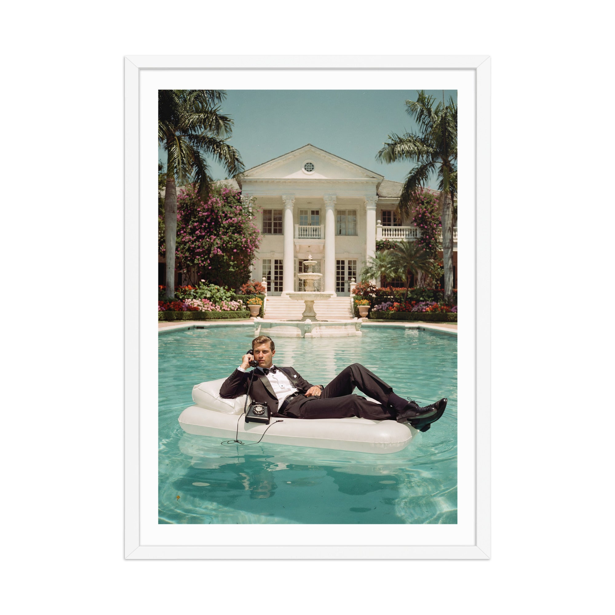 Man lounging on an inflatable pool float in a luxurious pool with a mansion in the background