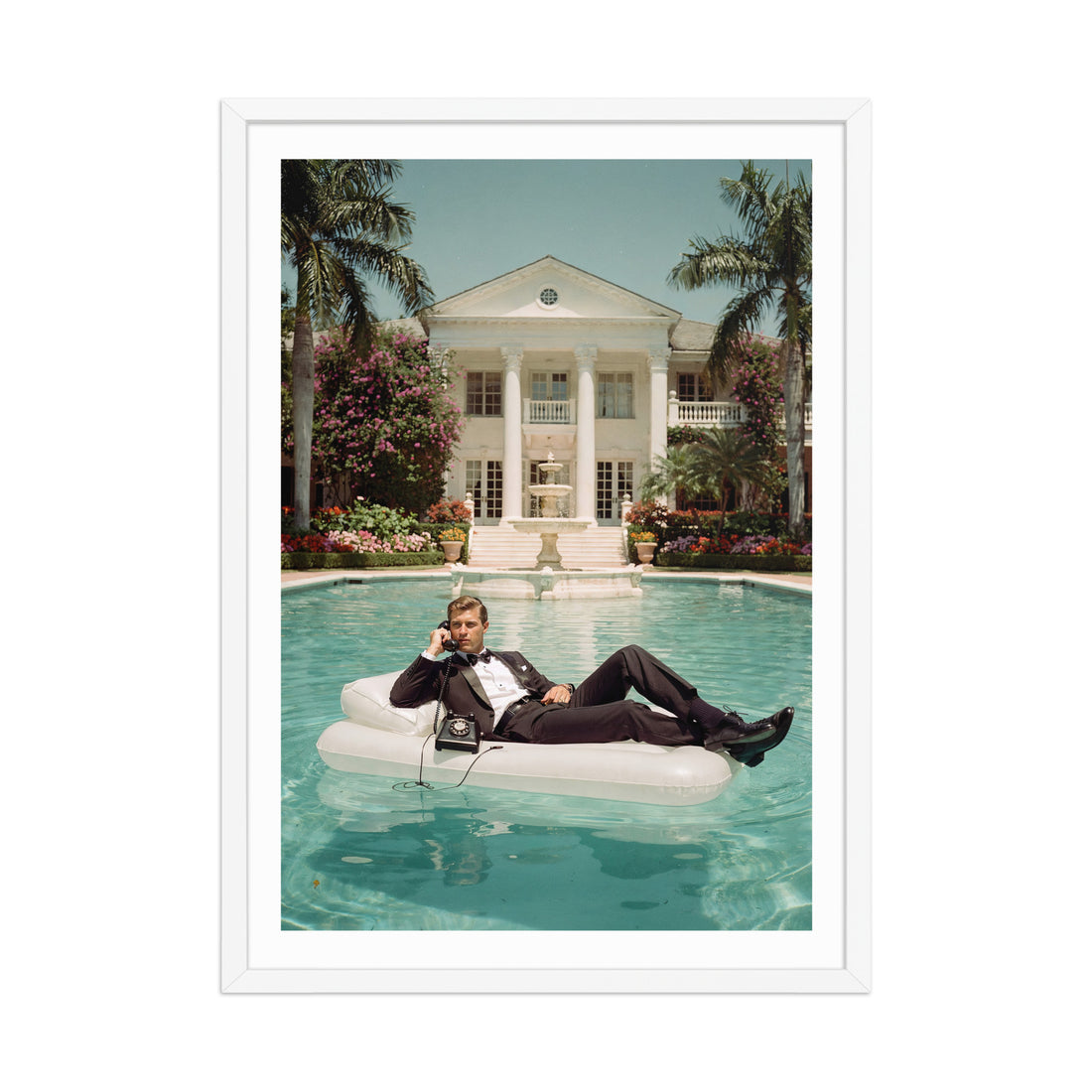 Man lounging on an inflatable pool float in a luxurious pool with a mansion in the background