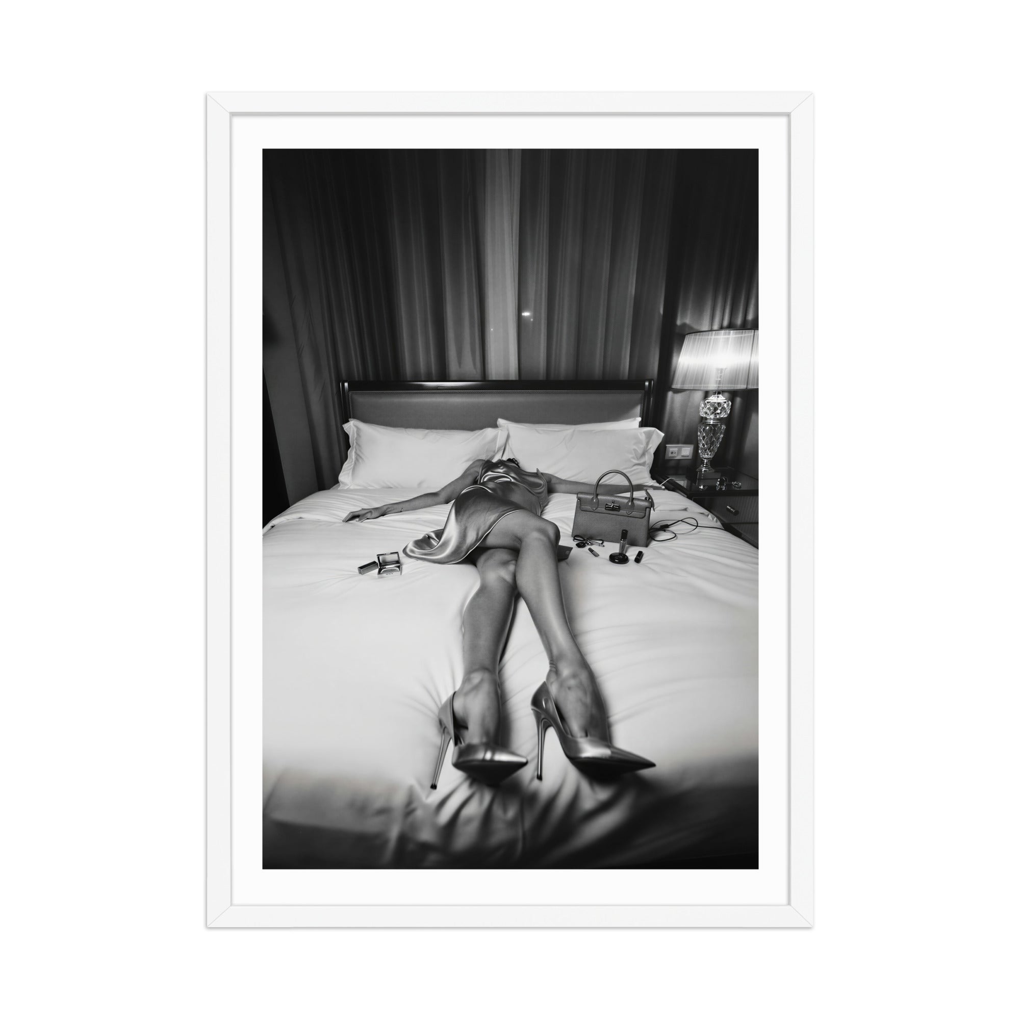 Person lying on a bed wearing high heels in a black and white photo.