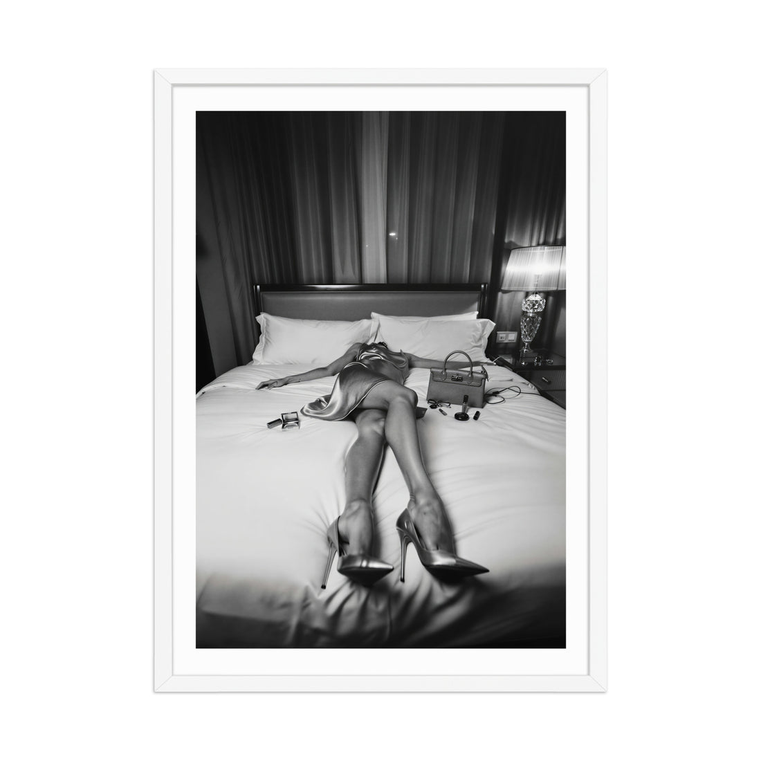 Person lying on a bed wearing high heels in a black and white photo.