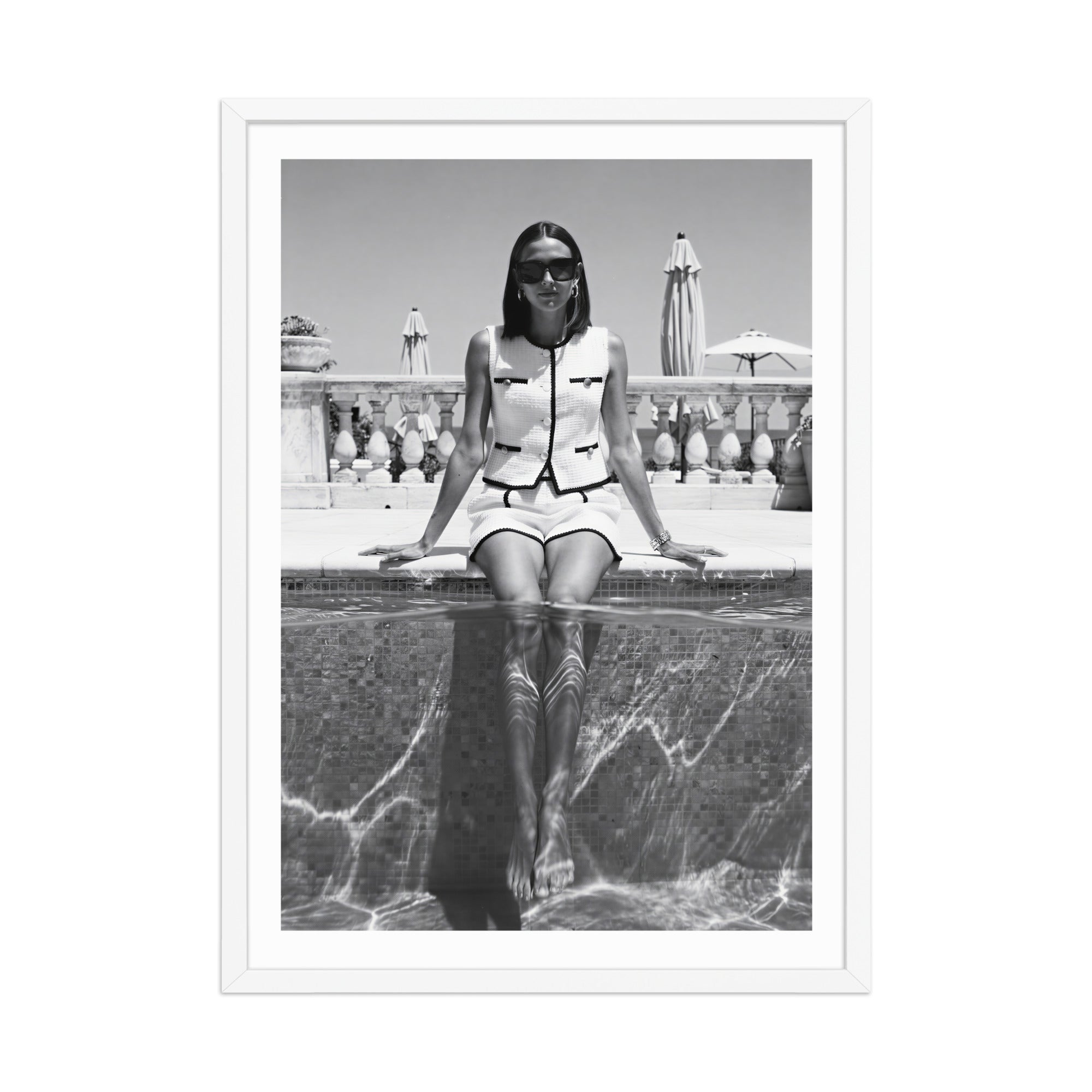 Black and white photo of a woman sitting by a pool with a fountain in the background.