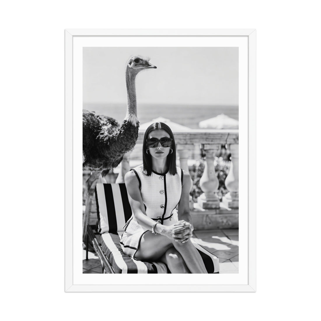 Black and white photo of a woman sitting on a striped chair with an ostrich next to her.