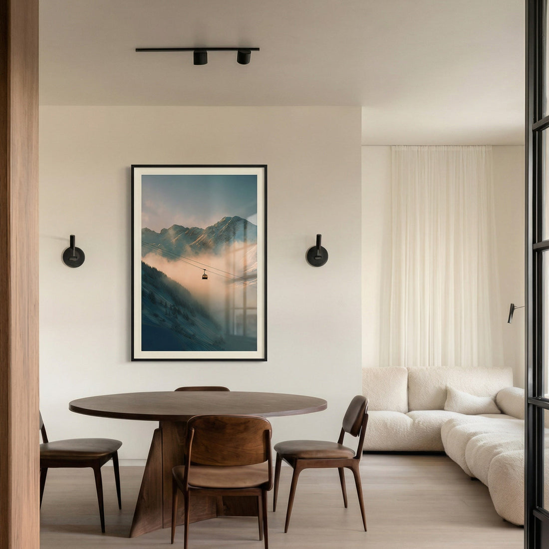 Modern dining area with a round table and chairs, framed artwork on the wall, and a sofa.